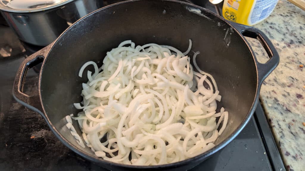 Sautéed onions in a black cast iron skillet for cooking or recipe preparation.