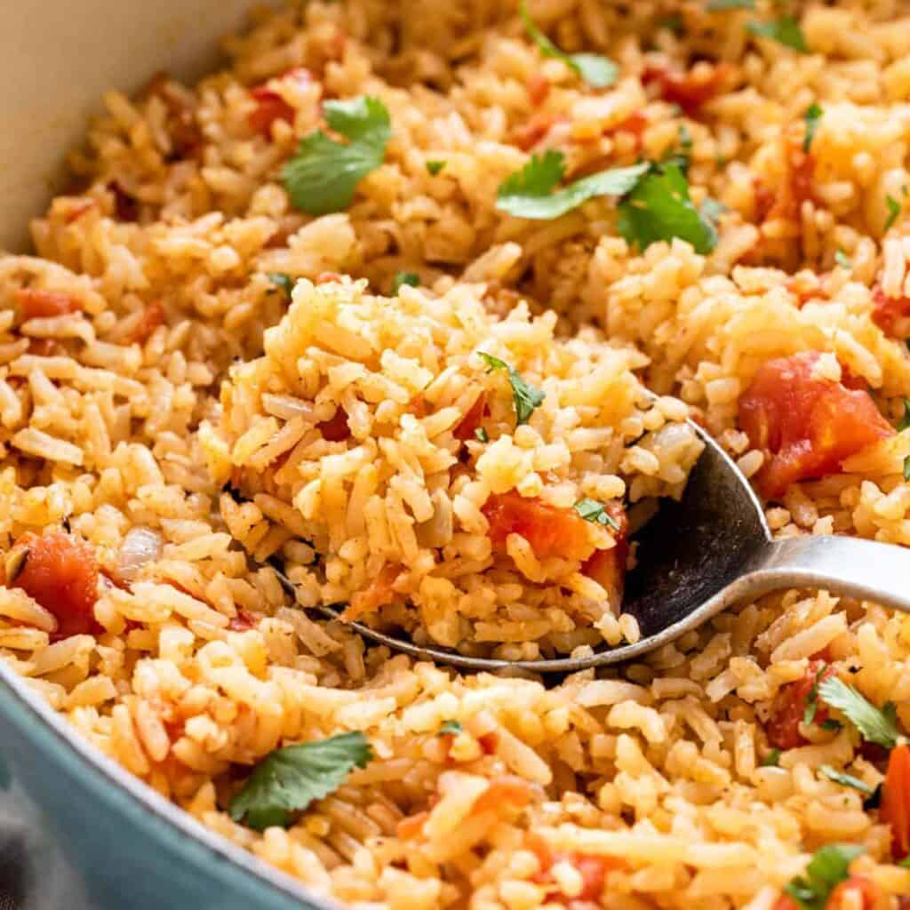 Spicy tomato and rice dish topped with fresh cilantro, served in a colorful skillet, close-up shot of flavorful Mexican rice, vibrant and appetizing homemade rice recipe, perfect for family dinner or party side dish.