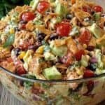 Fresh taco salad with tomatoes, lettuce, corn, black beans, and crispy tortilla strips in a glass bowl for a flavorful Mexican-inspired meal.