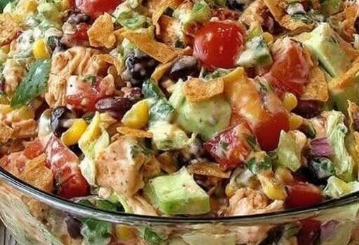 Fresh taco salad with tomatoes, lettuce, corn, black beans, and crispy tortilla strips in a glass bowl for a flavorful Mexican-inspired meal.