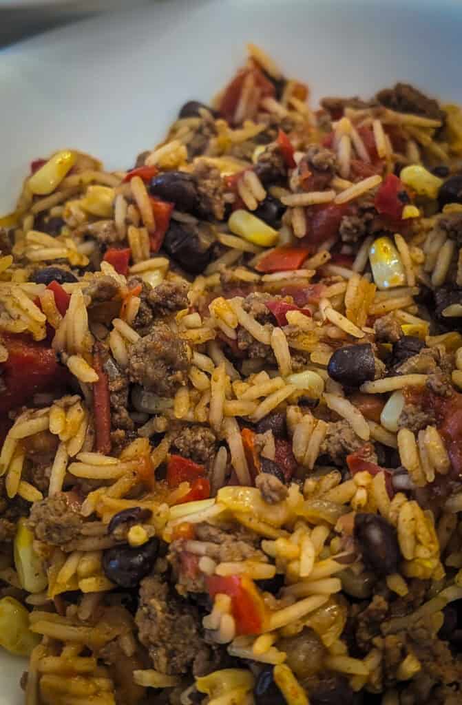 Ground beef and rice skillet with black beans, corn, and diced tomatoes. Hearty and flavorful comfort food dish perfect for any meal.