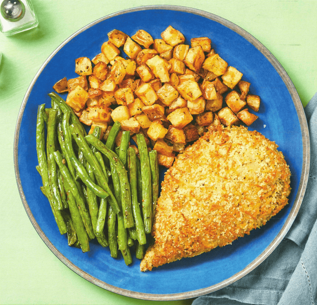Crispy baked chicken thigh with bread crumbs and green beans, served with roasted potatoes on a blue plate, delicious comfort food, healthy dinner idea.