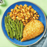 Crispy baked chicken thigh with bread crumbs and green beans, served with roasted potatoes on a blue plate, delicious comfort food, healthy dinner idea.