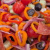 Colorful vegetable salad with cherry tomatoes, red onions, bell peppers, black olives, cucumbers, and pepperoni slices, vibrant and fresh, perfect for healthy snacking or meal prep.